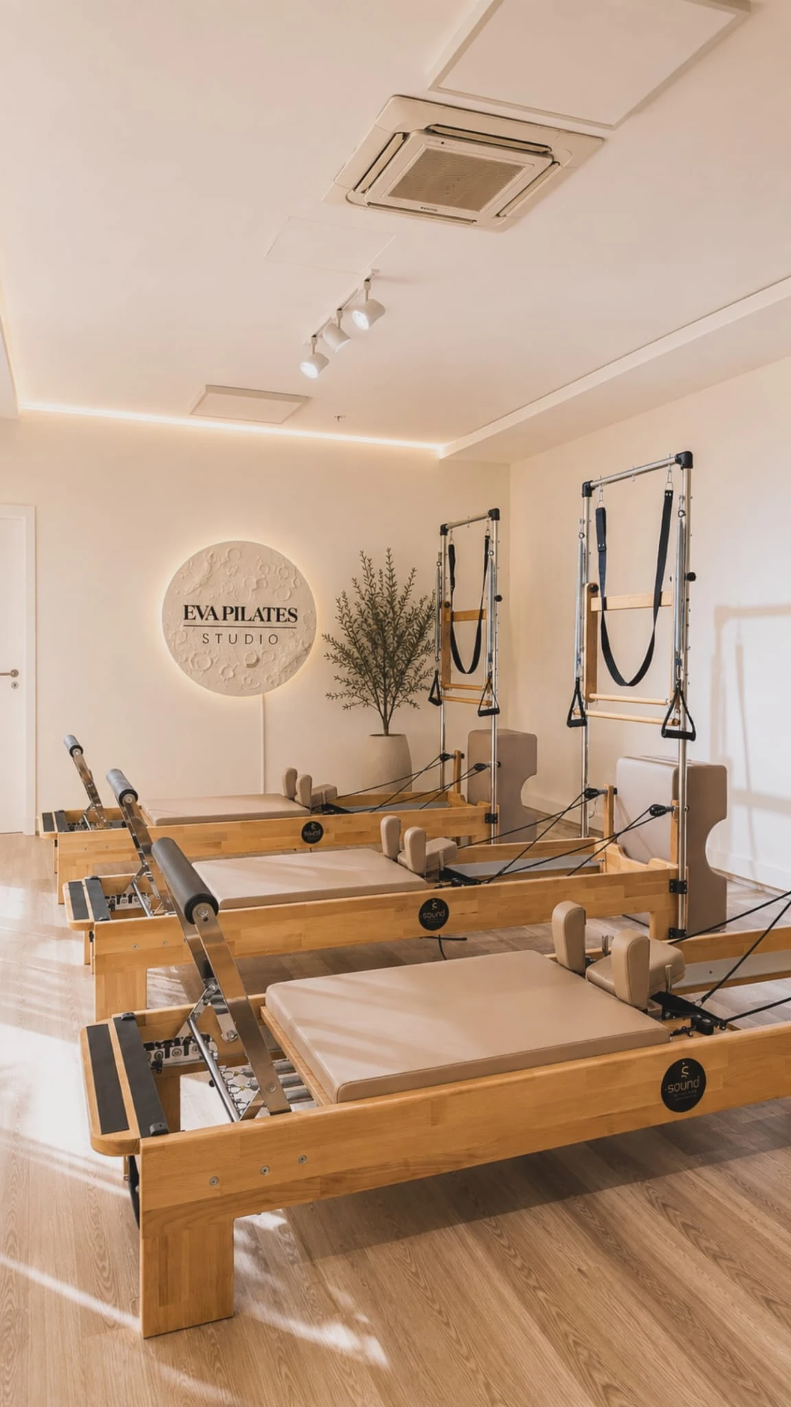Eva Pilates Studio'nun reformer salonu: ahşap reformer aletleri ve aydınlatmalı logo duvarı